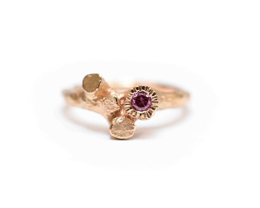 rose gold ring shaped like a tree trunk with roots holding a natural pink diamond