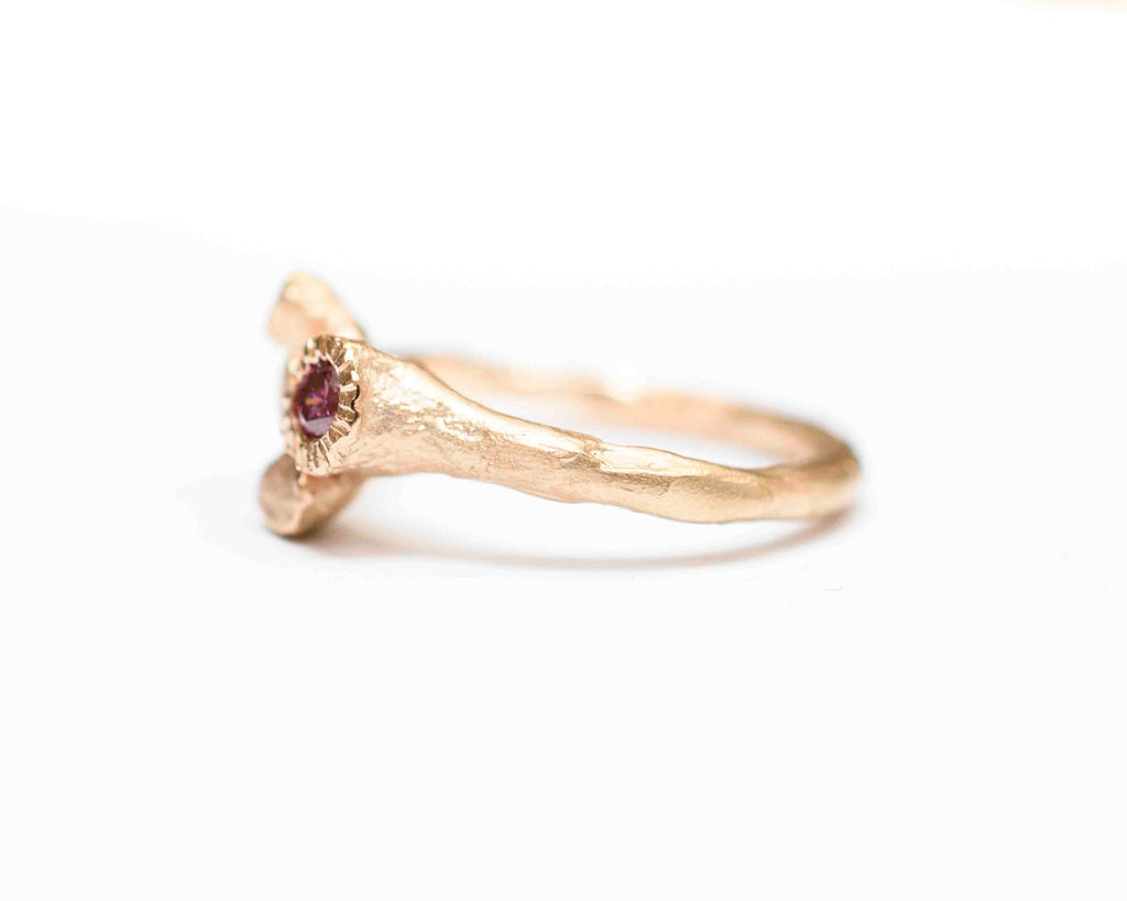 rose gold ring shaped like a tree trunk with roots holding a natural pink diamond